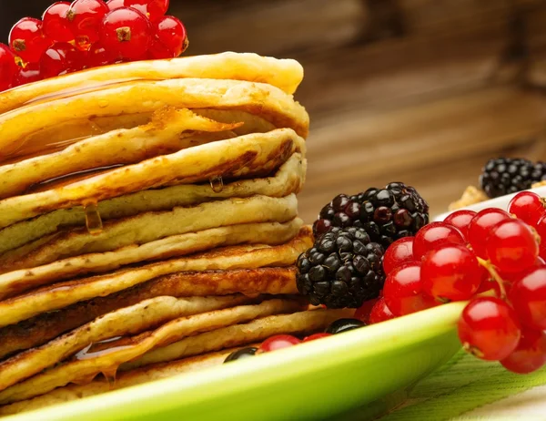 Läckra pannkakor med lönnsirap och färska bär på en tallrik — Stockfoto