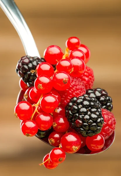 Frische Beeren auf einem Löffel vor hölzernem Hintergrund — Stockfoto