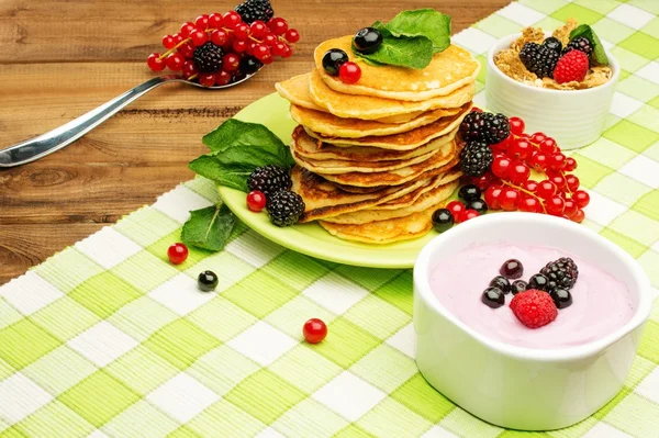 Healthy breakfast with pancakes, fresh berries and yoghurt on tablecloth in rural interior — Stock Photo, Image