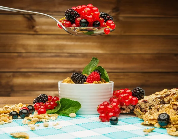 Healthy breakfast with muesli and berries on tablecloth in wooden rural interior — Stock Photo, Image