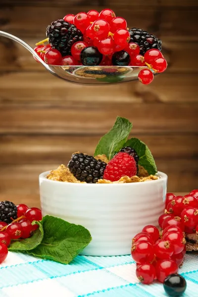 Healthy breakfast with muesli and berries on tablecloth in wooden rural interior — Stock Photo, Image