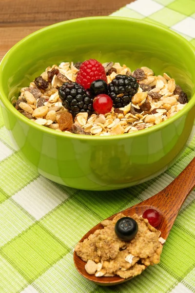 Wooden spoon and bowl with muesli and fresh berries on tablecloth — Stock Photo, Image