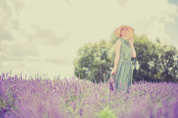 在长长的绿衣服和帽子在薰衣草田地中的女人 — 图库照片
