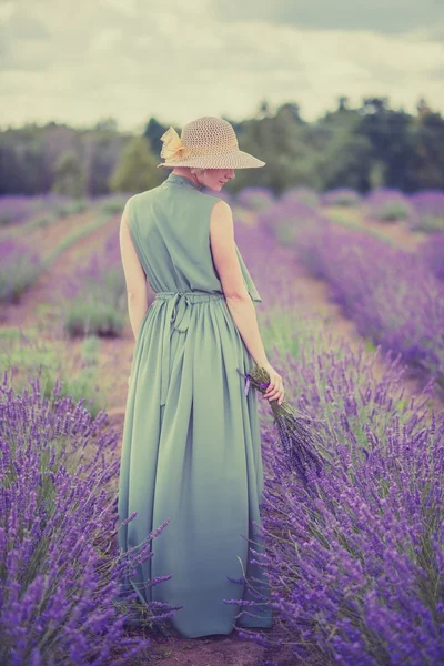 Kvinna i långa gröna klänning och hatt i ett lavendel fält — Stockfoto