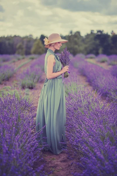 Kvinna i långa gröna klänning och hatt i ett lavendel fält — Stockfoto