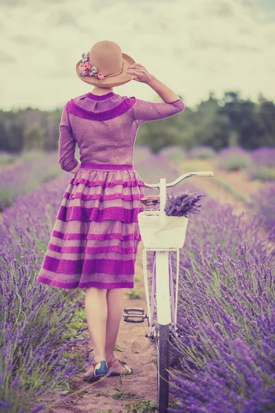 Vrouw in paarse jurk en hoed met retro fiets in Lavendel veld — Stockfoto