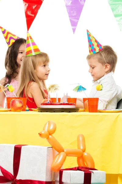 Kruppe fröhlicher Kinder feiert Geburtstag hinterm Tisch — Stockfoto