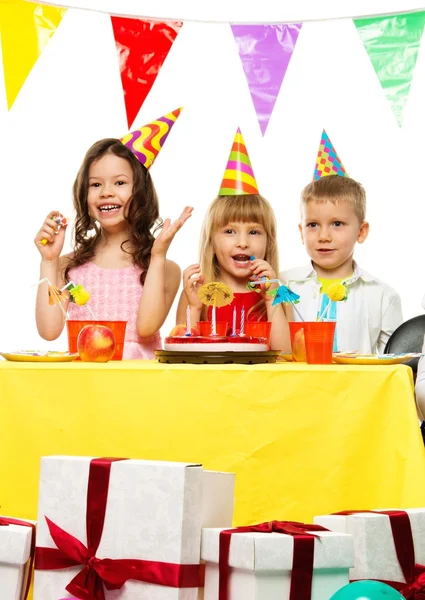 Kruppe fröhlicher Kinder feiert Geburtstag hinterm Tisch — Stockfoto