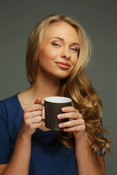 Mujer joven positiva con cabello largo y ojos azules sosteniendo la taza —  Fotos de Stock