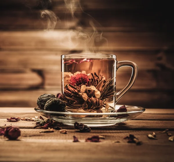 Glass cup with tea flower against wooden background — Stock Photo, Image