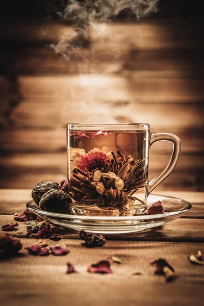 Glass cup with tea flower against wooden background — Stock Photo, Image