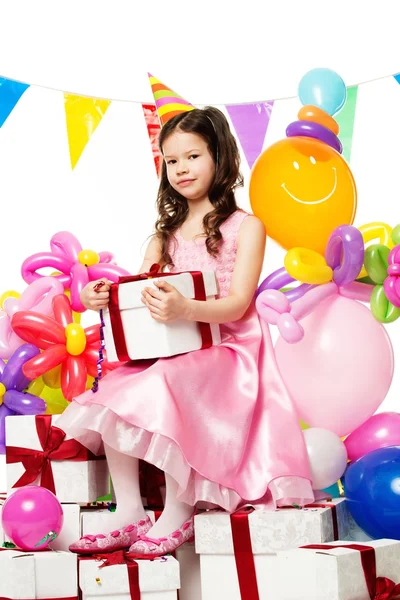 Hediye kutuları üzerinde oturan pembe elbiseli küçük kız — Stok fotoğraf