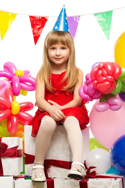 Malá holčička v červených šatech sedí na dárkové krabičky — Stock fotografie