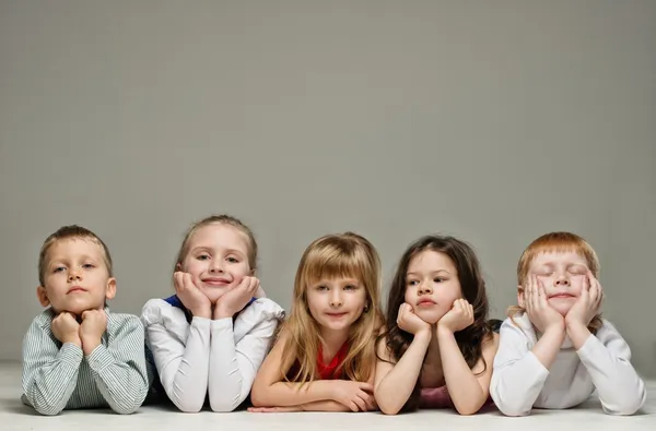 Groupe de petits enfants couchés dans une rangée isolé sur gris — Photo