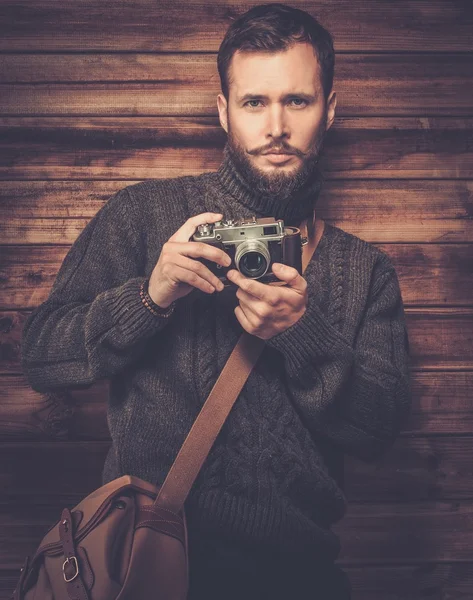 Pohledný muž nosí svetr vintage fotoaparátem v dřevěném domě interiéru — Stock fotografie