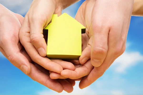 Les mains de l'homme et de la femme tenant la maison de papier conceptuel contre le ciel bleu — Photo