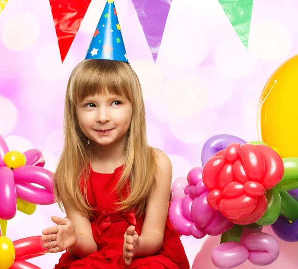 Klein meisje in een rode jurk zittend op geschenkdozen — Stockfoto