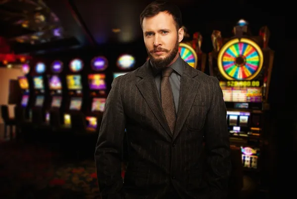 Handsome well-dressed man against slot machines in a casino — Stock Photo, Image