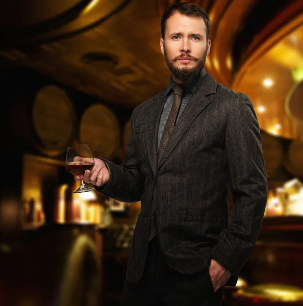 Hombre guapo bien vestido en chaqueta con vaso de bebida en el interior del restaurante — Foto de Stock