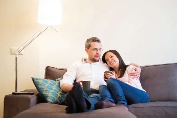 Jovem casal positivo em um sofá em casa interior — Fotografia de Stock