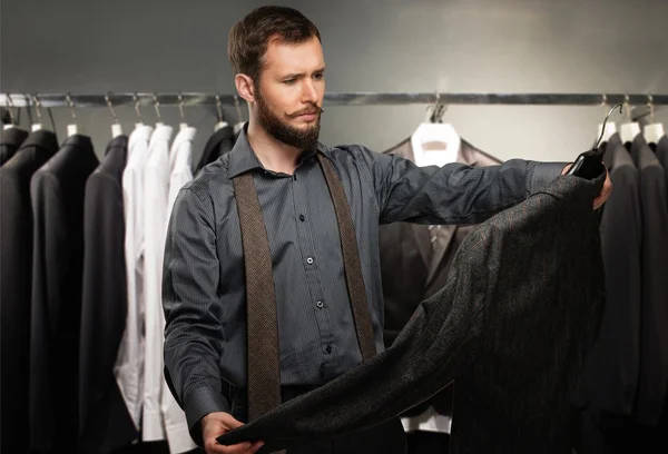 Snygg man med skägg väljer jacka i en butik — Stockfoto