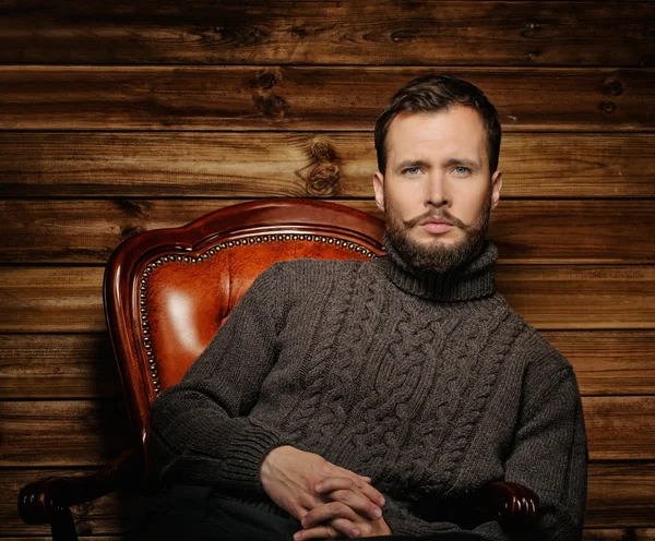 Schöner Mann mit Strickjacke im ländlichen Holzhaus-Interieur — Stockfoto