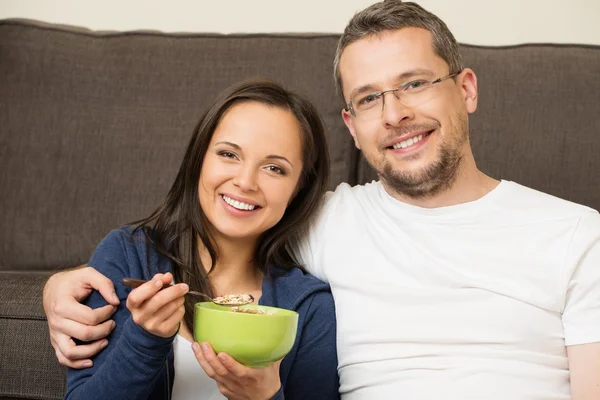 Alegre pareja joven con tazón de muesli en el interior del hogar — Foto de Stock