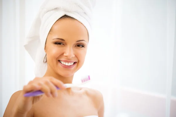 Young woman with towel on her head using toothbrush — Stock Photo, Image