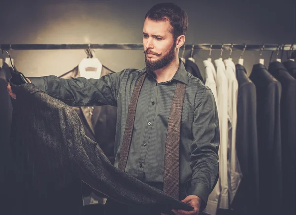 Hombre guapo con barba eligiendo chaqueta en una tienda — Foto de Stock