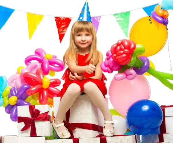 Klein meisje in een rode jurk zittend op geschenkdozen — Stockfoto