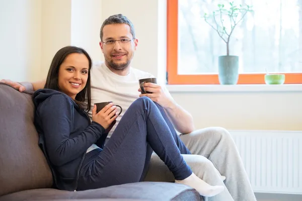 Jovem casal alegre em um sofá em casa interior — Fotografia de Stock