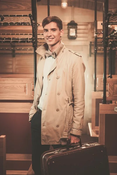 Beau jeune homme avec valise en manteau à l'intérieur du train ancien entraîneur — Photo