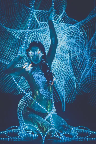 Bella donna con arte del corpo incandescente in luce ultravioletta e sfondo freezelight — Foto Stock