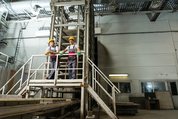 Two men in a safety hats on a factory — Stock Photo, Image