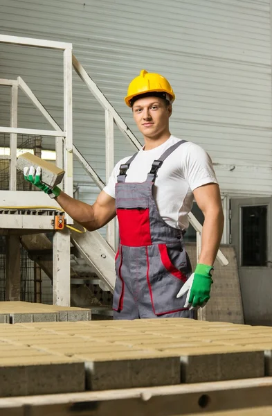 Young worker near conveyor belt with paving stone  on a factory — Stock Photo, Image