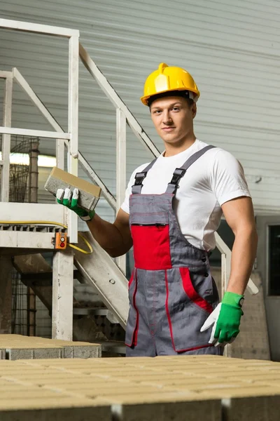 Junger Arbeiter nahe Förderband mit Pflasterstein auf Fabrik — Stockfoto