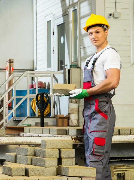 Young worker near conveyor belt with paving stone  on a factory — Stock Photo, Image