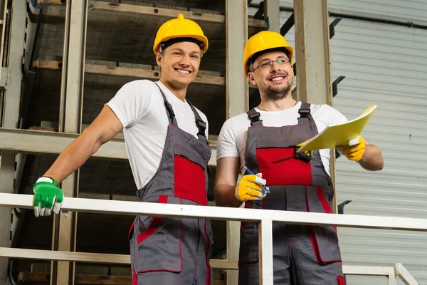 Dos trabajadores positivos en sombreros de seguridad en una fábrica — Foto de Stock