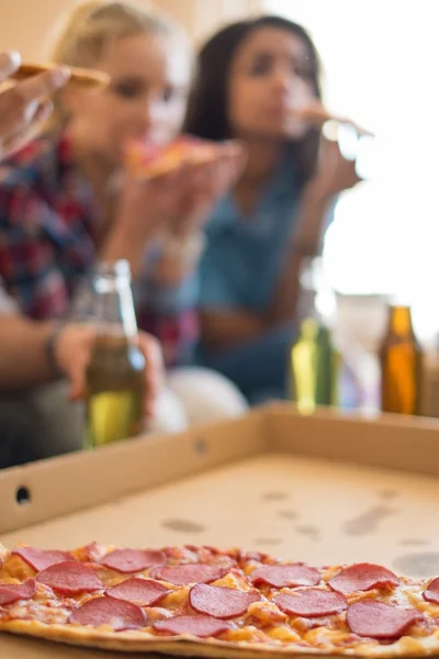 Grupo de jovens amigos multi étnicos com pizza e garrafas de bebida comemorando em casa interior — Fotografia de Stock