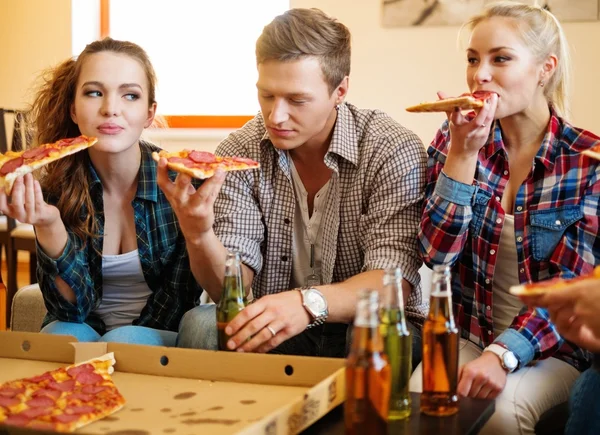 Group of friends eating pizza in home interior — Stock Photo, Image