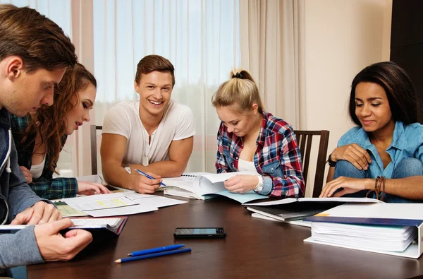 Multi etniska grupp studenter som förbereder sig för tentor i heminredning bakom tabell — Stockfoto