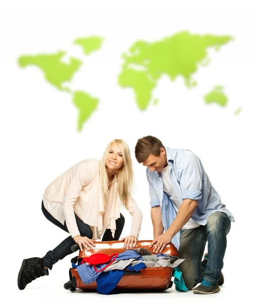 Jovem casal mala de embalagem para uma viagem contra o mapa do mundo — Fotografia de Stock