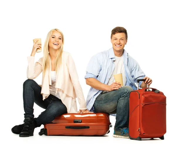 Young couple with coffee cups sitting on suitcases — Stock Photo, Image