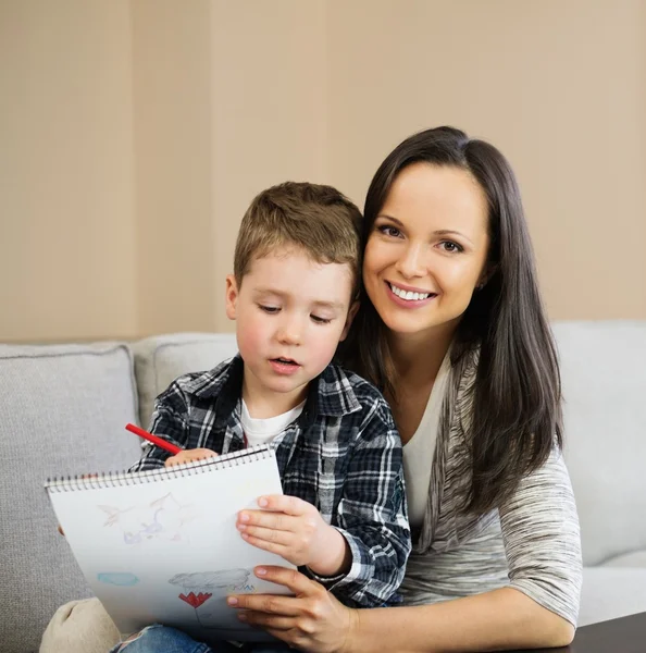 Glückliche junge Mutter mit ihrem Sohn beim Zeichnen zu Hause — Stockfoto