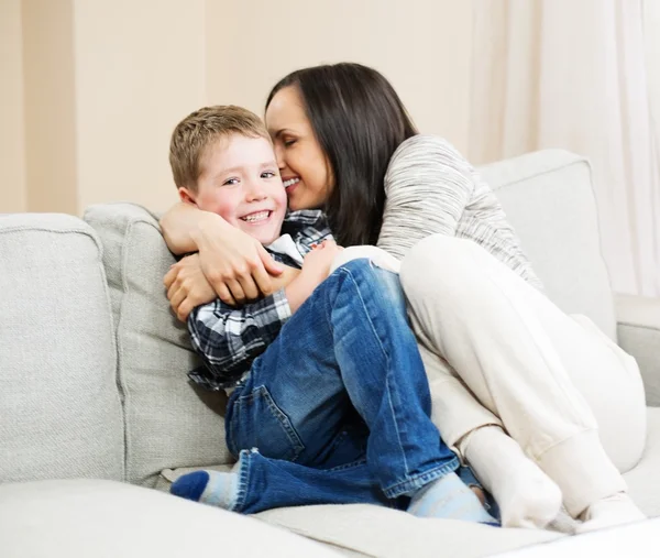 Szczęśliwa młoda matka z synem na kanapie w domu wnętrza — Zdjęcie stockowe