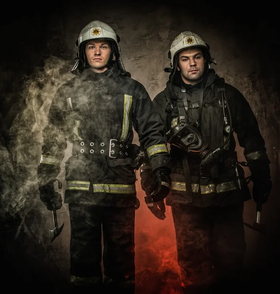 Due pompieri con casco e ascia in un fumo — Foto Stock