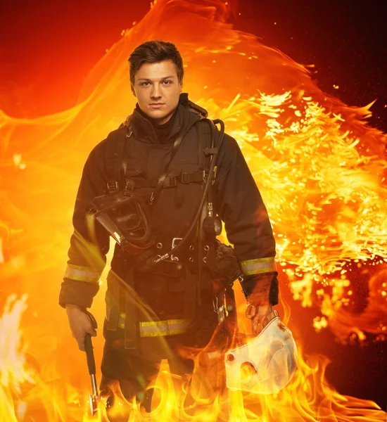 Пожежник з шоломом і сокирою в полум'ї — стокове фото