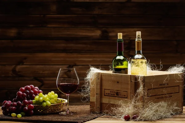 Flessen van rode en witte wijn, glas en druivenmost op een houten interieur — Stockfoto