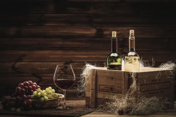 Botellas de vino tinto y blanco, copa y uva en un interior de madera —  Fotos de Stock