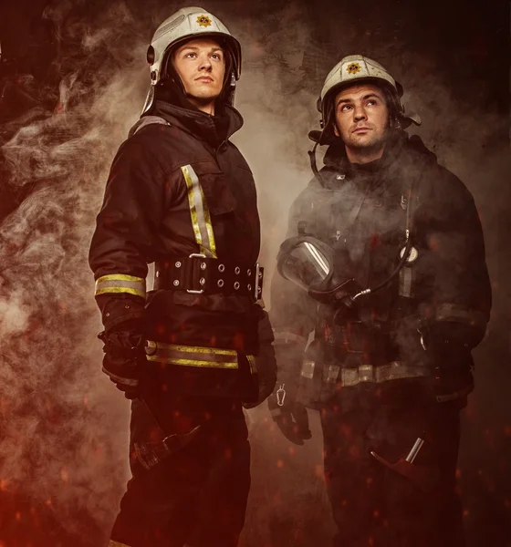Двоє пожежників з шоломом і сокирою в диму — стокове фото